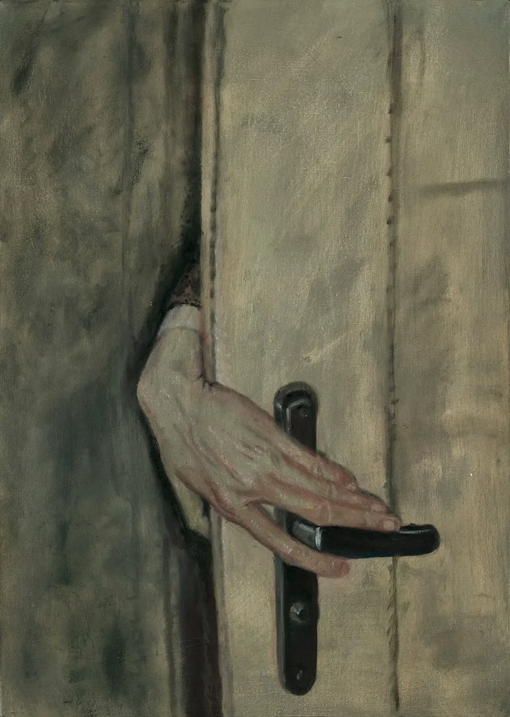 Una mano si posa sulla maniglia di una porta.
